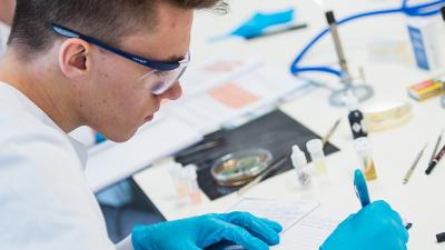 A biosciences student writing notes during experiment