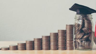 Coins stacked up with a jar and a graduate cap on top